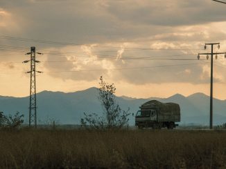 Minh họa xe tải chạy trên tuyến đường dưới đường dây điện lúc hoàng hôn